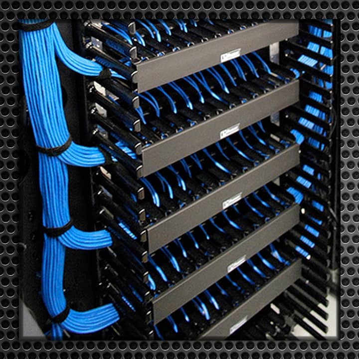 Detailed view of a neatly organized network cabling system with rows of blue cables and black racks in a data center.