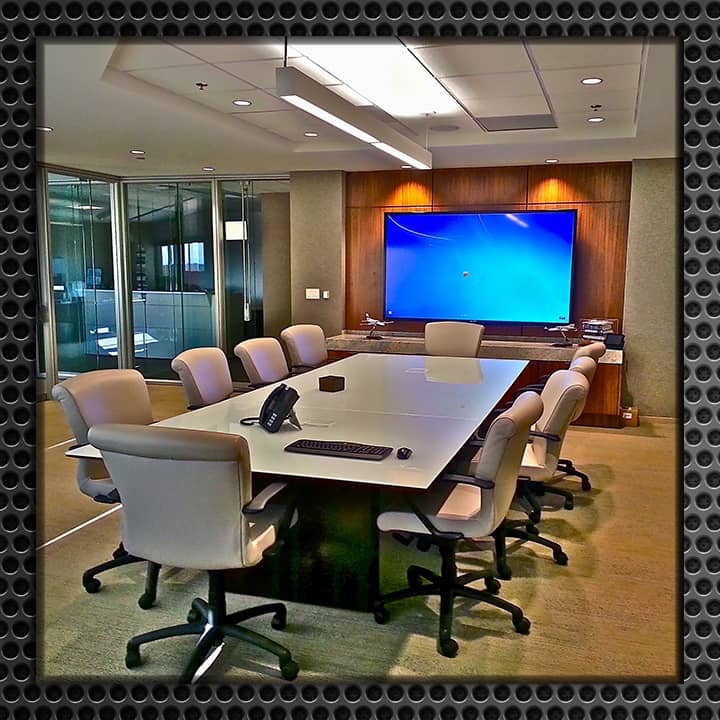 A well-appointed modern conference room with a large table, comfortable chairs, and a big flat-screen TV on the wall.
