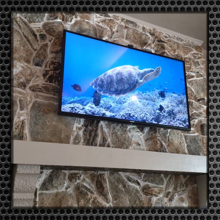 Flat-screen TV mounted on a unique stone wall displaying a vivid underwater scene with a turtle.