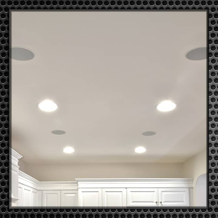 Elegant white room with flush-mounted ceiling speakers and recessed lighting, showcasing a modern and clean design.