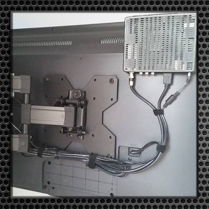 Detailed view of the back of a mounted TV showing an organized wire management system and mounting brackets.